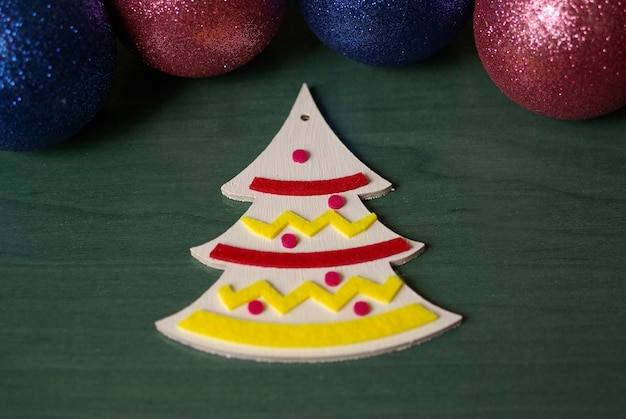 White wooden Christmas tree with felt decor on a green background