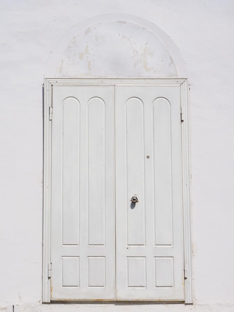 A white wooden door on a white wall The old door