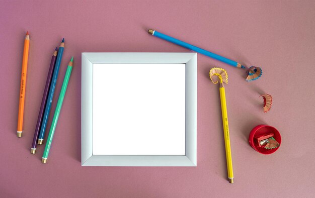 White wooden photo frame, colored pencils and a small alarm clock