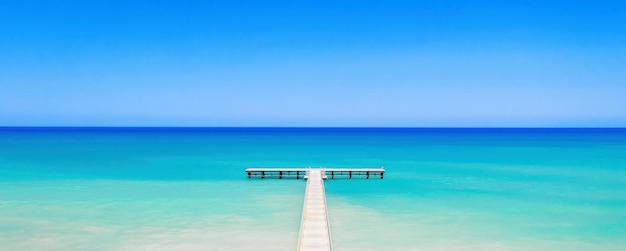 White wooden pier over bright turquoise sea water panorama of tropical island coast