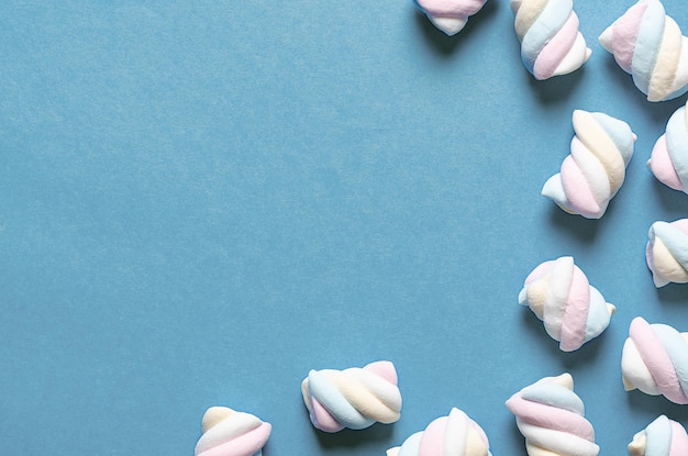 White, yellow, pink, and light blue marshmallows on light blue background.