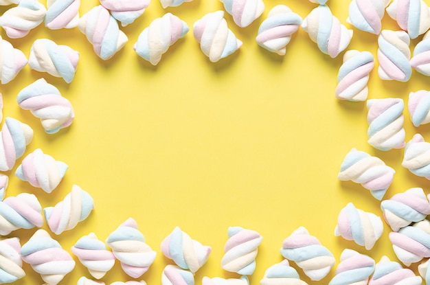 White, yellow, pink, and light blue marshmallows on yellow background.