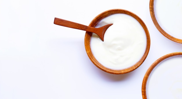 White yogurt in wooden bowl on white background.