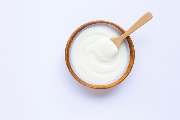 White yogurt in wooden bowl on white