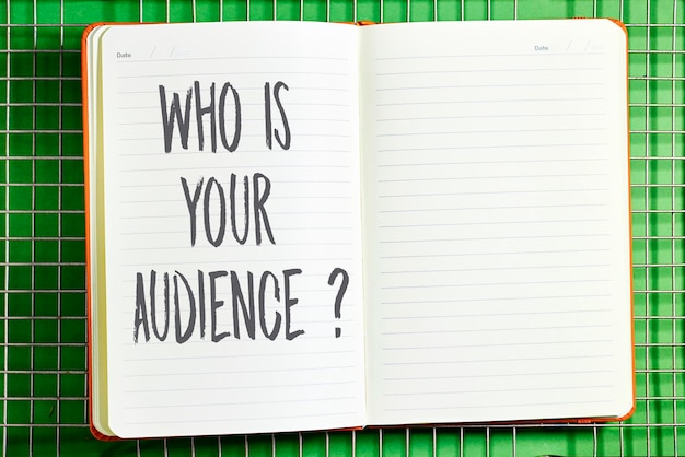 Who is your audience word on notebook above fence background