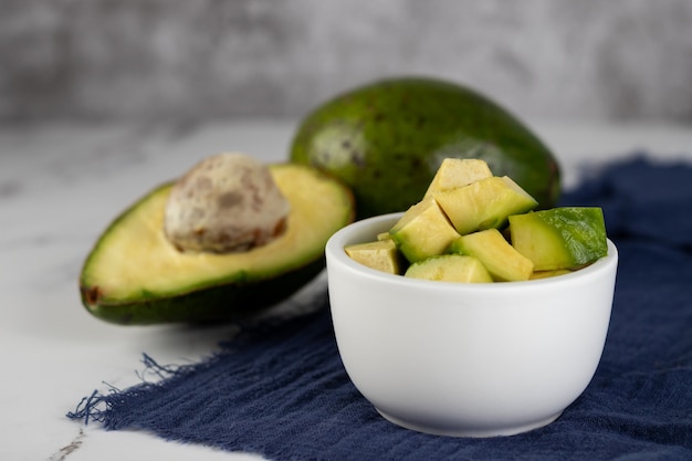 Whole avocado, cut in half and diced in a white bowl.