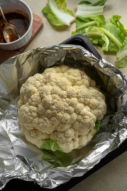 Whole cauliflower head with herbs and spices Cooking process of roasted cauliflower top view