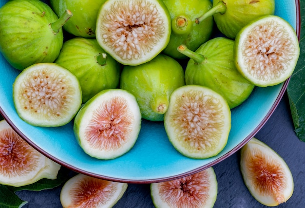 Whole and cut green figs, with fig leaves. 