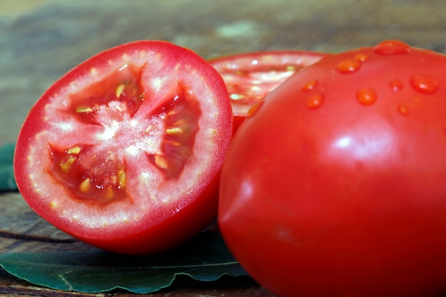 Whole and cut tomatoes on wooden background