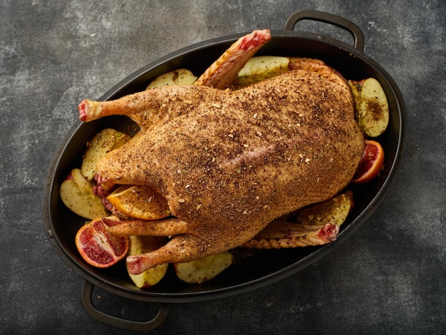 The whole duck is ready to be roasted with apples and oranges in spiced applesauce