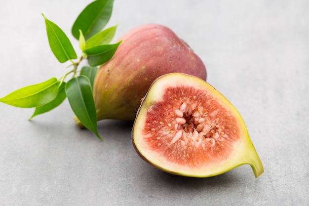 Whole figs and one fig sliced in half on top of a gray table.