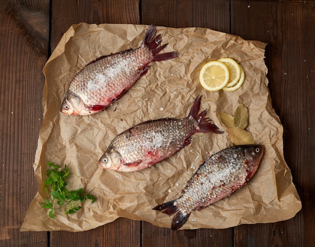 Whole fresh crucian fish with scales on a crumpled brown piece of paper