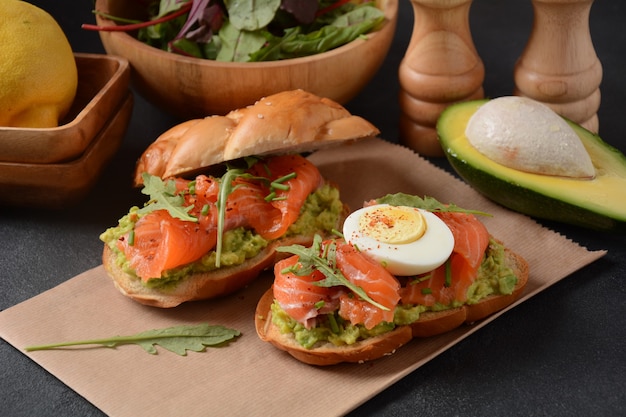 Whole grain bread sandwich with avocado paste and salmon, egg, and arugula leaves