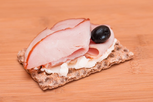 Whole grain crispbread with ham cream cheese and olives