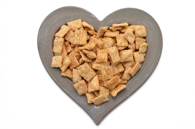 Whole grain flakes cinnamon pads in a heartshaped frame on a white background