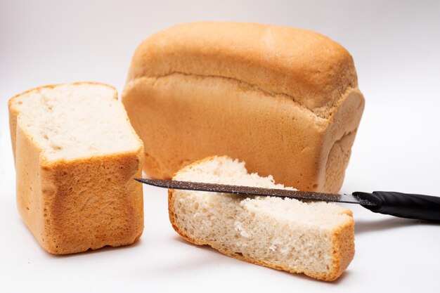 Whole grain loaf and Slices of fresh bread with knife for cut on white background.