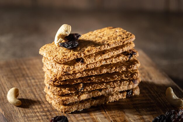 Whole grain oat cookies, biscuit crackers with nut kernels and raisins, wooden background. High quality photo