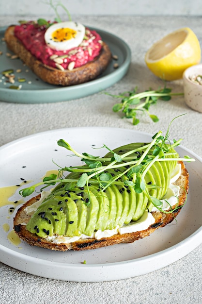 Whole grain toast with cream cheese, avocado, beetroot hummus, seeds, egg and microgreens