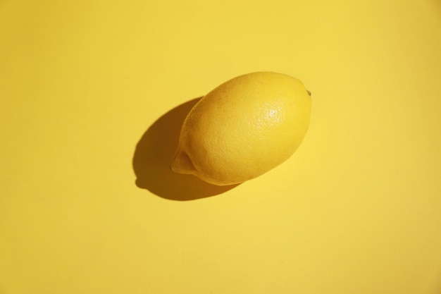 Whole lemon on a bright yellow color background