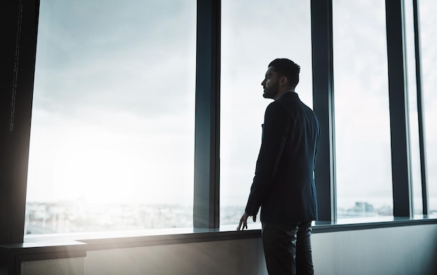 On a whole new level Shot of a young businessman looking thoughtfully out of an office window