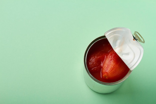 Whole peeled tomatoes in can on green background