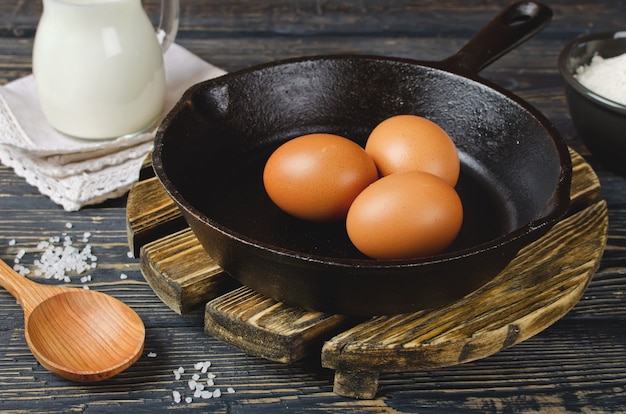 Whole raw eggs in a pan on a wooden table. Ingredients for the omelet