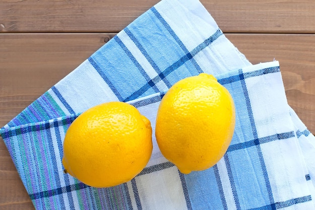 Whole ripe lemons on a wooden table on a cotton towel food products