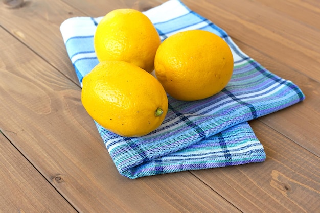 Whole ripe lemons on a wooden table on a cotton towel food products