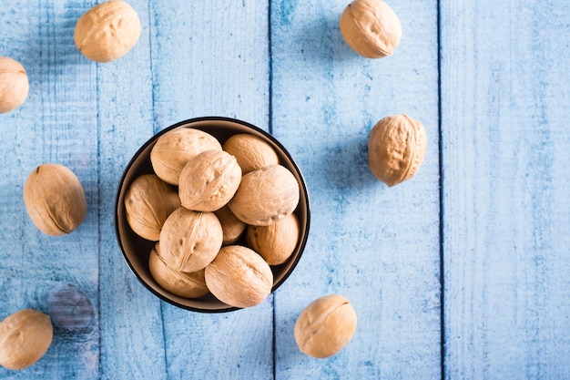 Whole ripe walnuts in shell in a bowl on the table Organic food Top view