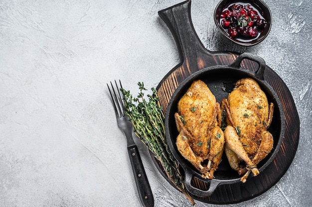 Whole roast quails in a pan.  White background. Top view. Copy space.