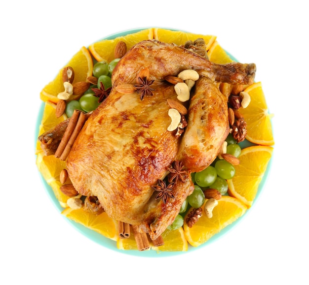 Whole roasted chicken with grapes oranges and spices on blue plate isolated on white