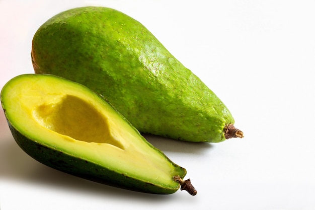 Whole and sliced avocado on white background