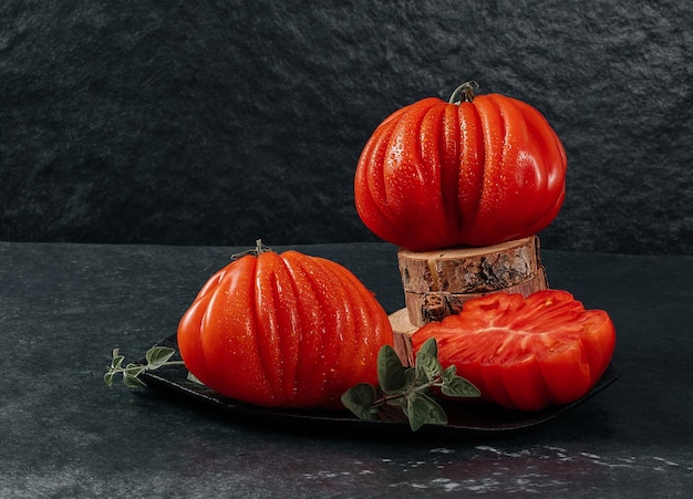 Whole and sliced fresh Raf Coeur De Boeuf beef tomatoes with oregano