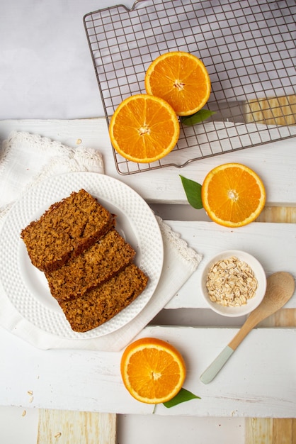 Whole and sliced healthy orange cake with split oranges on table