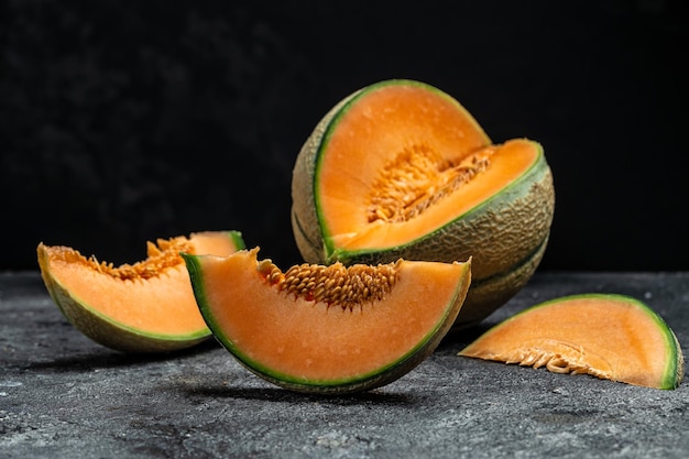 Whole and sliced of Japanese melons or cantaloupe on dark background place for text