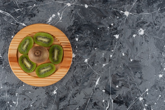 Whole and sliced kiwi fruits placed on a wooden board.