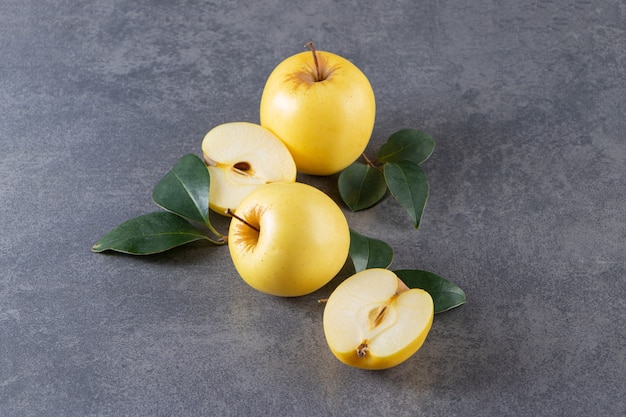 Whole and sliced yellow apple fruits placed on stone table . 