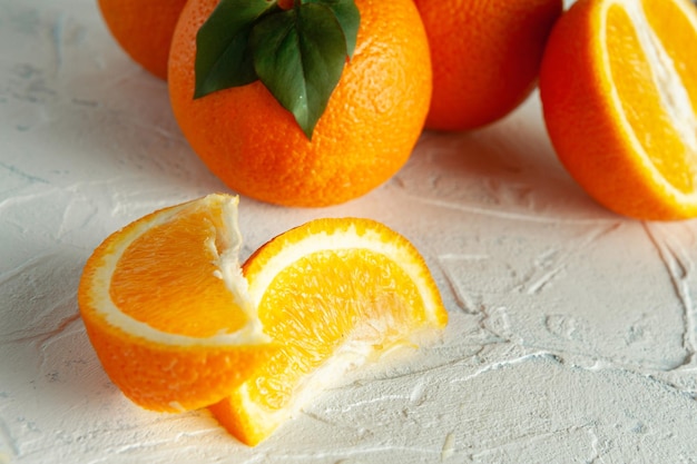 Whole and slices of orange with green leaves on a light texture view from above with a place for text Closeup white texture