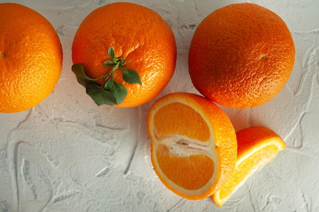 Whole and slices of orange with green leaves on a light texture view from above with a place for text Closeup white texture