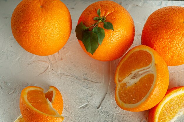 Whole and slices of orange with green leaves on a light texture view from above with a place for text Closeup white texture