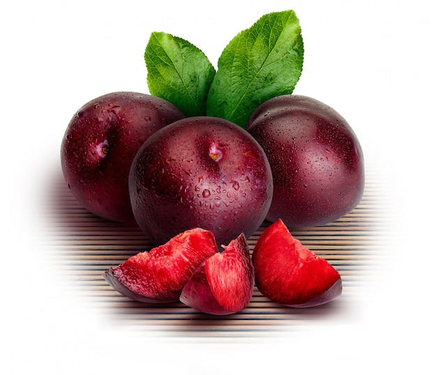 whole and slices of plums on white background