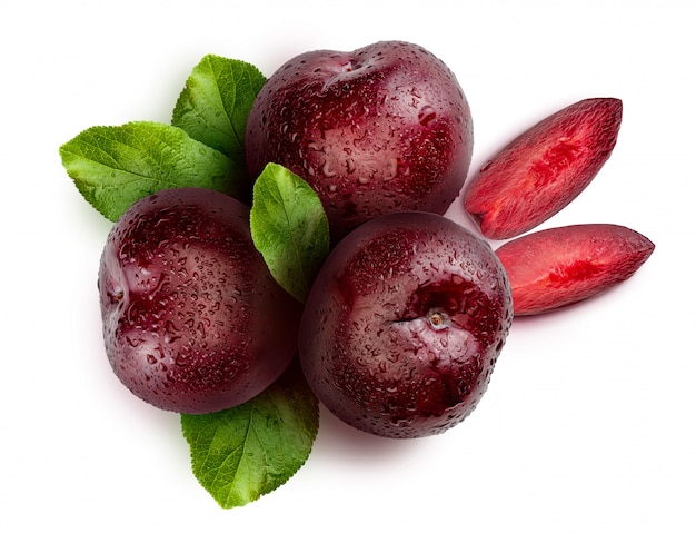 whole and slices of plums on white background