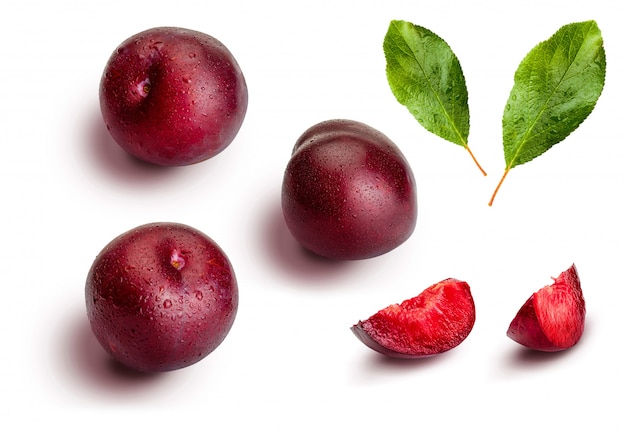 whole and slices of plums on white background