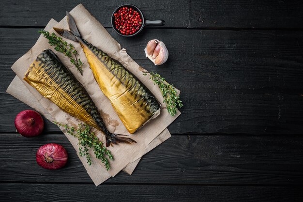 Whole smoked fish mackerel, on black wooden table background, top view flat lay  with copy space for text