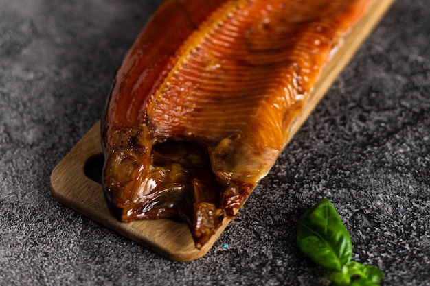 Whole smoked trout on a wooden board on a dark background Snack