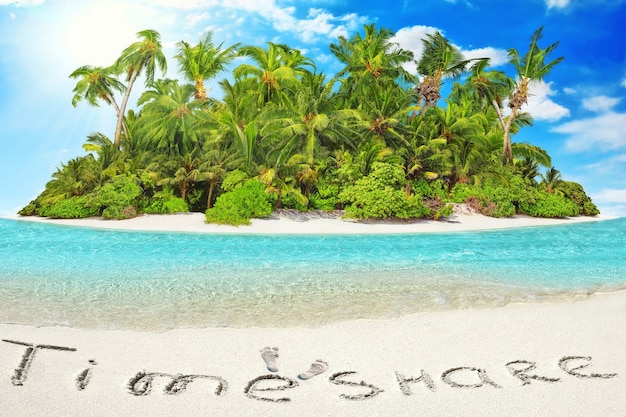 Whole tropical island within atoll in tropical Ocean. Uninhabited and wild subtropical isle with palm trees. Inscription "TimeShare" in the sand on a tropical island,  Maldives.