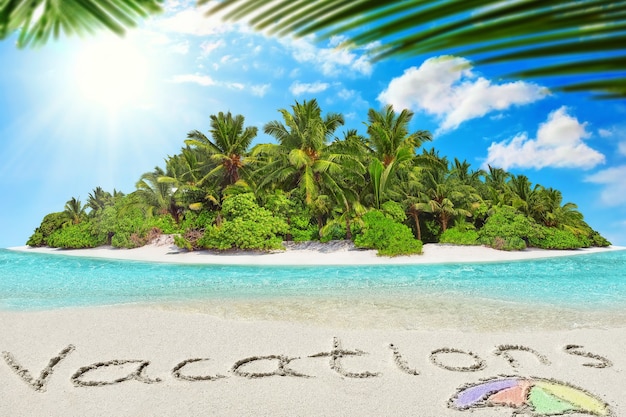 Whole tropical island within atoll in tropical Ocean. Uninhabited and wild subtropical isle with palm trees. Inscription "Vacations" in the sand on a tropical island,  Maldives.