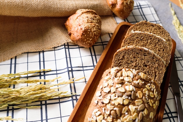 Whole Wheat Rye Bread Loaf is cut and placed on a wooden plate.