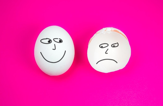 Whole White egg with smile and broken egg with Sad or Negative emotion on the pink background Copy space Minimalist original and creative photo Beautiful wallpaper Different emotion