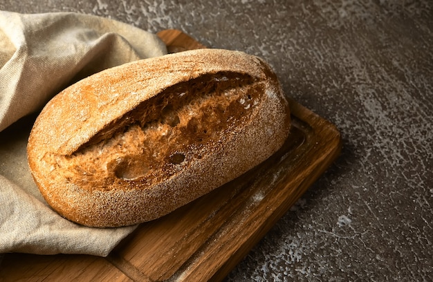 Wholegrain rye bread on a cutting board on grey surface